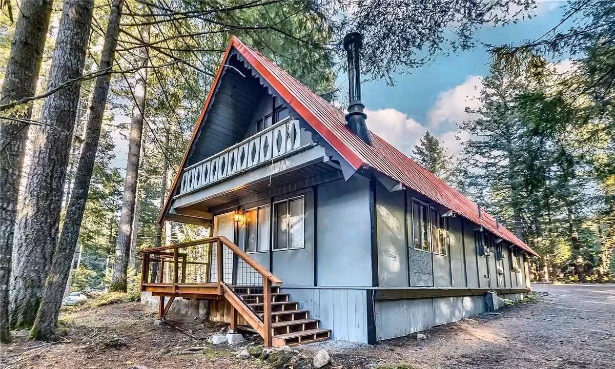 Tiny Timber A-frame at dusk, red roof under tall trees
